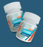 Frascos de suplemento Oxandrol, cápsulas para fitness y culturismo sobre fondo azul.